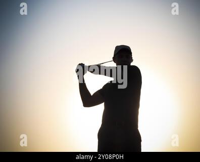 Männlichen Golfer Golfspielen im Sonnenuntergang Stockfoto