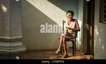 Baracoa, Kuba am 7. Januar 2016: In einem kubanischen Haus genießt eine alte Frau ein Bier in der Sonne Stockfoto