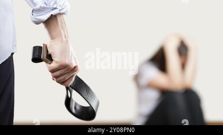 Familiengewalt und Aggressionskonzept, wütender Mann erhob Bestrafung Hand hielt Ledergürtel über verängstigte oder verängstigte Frau, die an der Wand c saß Stockfoto