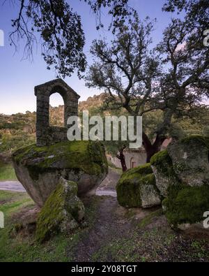 Alte Ruine Steingebäude bedeckt mit Moos in der Nähe der Kapelle Sao Pedro mit Bäumen und Felsblöcken in Monsanto, Portugal, Europa Stockfoto