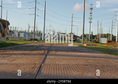 Baustellenmatten für vorübergehende Straßenzugänge mit geringer Sicht über das Gras zum Schutz vor schweren Lasten. Weite Schuss über braunen Matten am späten Nachmittag Sonne Stockfoto