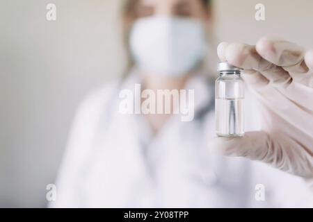 Frau Arzt oder Krankenschwester in Uniform und weißen Handschuhen tragen Gesichtsmaske schützende im Labor, halten Medizin Flüssigkeit Impfstoff Fläschchen Vorbereitung für injec Stockfoto