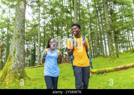 Afrikanisches Paar, das im Frühjahr einen Tag in der Natur beim Wandern in einem grünen Wald genießt Stockfoto