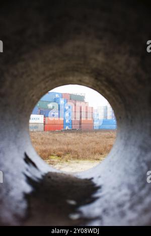 Blick durch ein Rohr auf einen Stapel Container im Hafen von Rotterdam, Niederlande Stockfoto