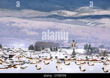 Bansko, Bulgarien Antenne Stadt Winter mit Schnee Häuser Dächer und St. Trinitatis Kirche Turm, Panorama der bulgarischen Skigebiet Stockfoto