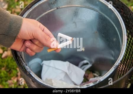 Nahaufnahme der männlichen Hand, die zerbrochene Zigarette in den Mülleimer wirft. Aufhören zu rauchen und gesund Leben Konzept. Stockfoto