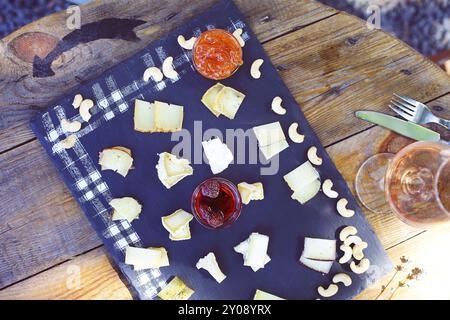 Traube, Einstellen von verschiedenen Arten von Käse mit einem Glas rosa Wein auf dem Tisch im Garten Stockfoto