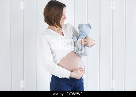 Schwangere Frau Profil hält einen Teddybär Stockfoto