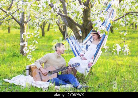 Schwangere paar im blühenden Garten beim Picknick. Zeit zum Faulenzen Stockfoto