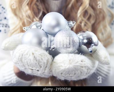 Junge blonde Frau mit Silber dekorative Kugeln mit weißen Handschuhen. Nahaufnahme Stockfoto