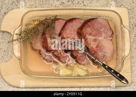 Geräuchertes Schweinefleisch mit Zwiebeln in einer Pfanne. Abendessen, Lende. Geräuchertes Schweinefleisch in einer Glaspfanne Stockfoto