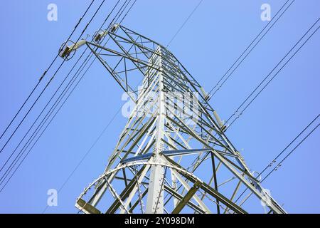 Ein hoher elektrischer Pylon aus Metall unterstützt mehrere Kabelsätze, die für die Übertragung von Elektrizität unerlässlich sind, wolkenloser klarer blauer Himmel. Stockfoto