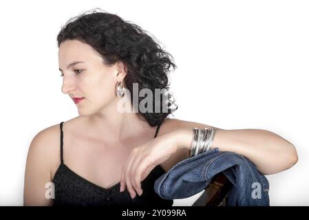 Ein junges Model, Mitte 20, sitzt auf einem hölzernen Stuhl mit einer blauen Jeansjacke Stockfoto