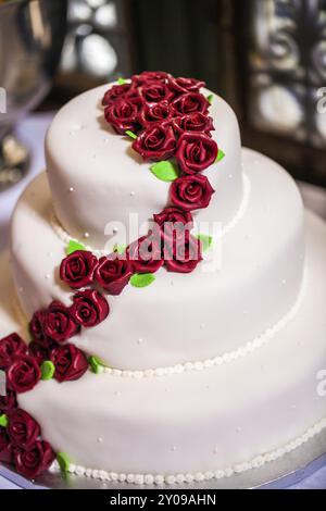 Weiße Hochzeitstorte mit roten Marzipanrosen Stockfoto