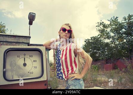 Blondes Mädchen hält Hände auf ihren Kopf stehend auf beschädigte Tankstelle Stockfoto