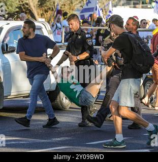 Jerusalem, Israel. 1. September 2024 Polizeibeamte verhaften Michal Deutsch, einen führenden Demonstranten bei einer Demonstration in Jerusalem. Die Demonstration forderte die Regierung auf, dringend eine Einigung mit der Hamas zu erzielen, bevor weitere Geiseln getötet werden. Die Polizisten tragen Michal in ihren Gliedmaßen. Quelle: Yoram Biberman/Alamy Live News. Stockfoto