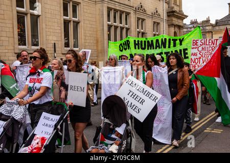 Eine Gruppe von Menschen, die während einer Demonstration in Bath England palästinensische Fahnen und Protestzeichen auf einer Straße halten Stockfoto