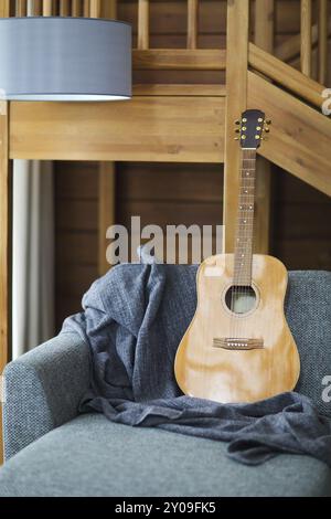 Gemütliches Wohnzimmer mit Gitarre auf dem Sofa im Holzhaus Stockfoto