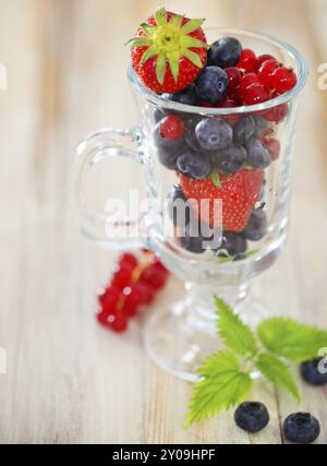 Köstliches frisches Obst im Glasbecher auf dem Holztisch Stockfoto