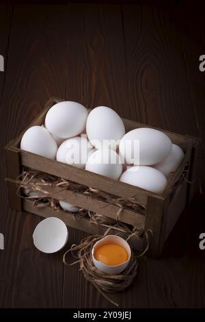 Haufen von frischen weißen Eiern in einer Holzkiste auf braunem Hintergrund Stockfoto