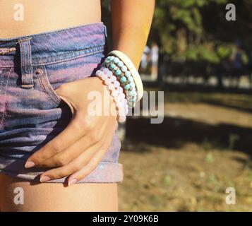 Mädchen tragen Armband in Denim-Shorts auf dem Festival der Farbe Holi. Nahaufnahme Stockfoto