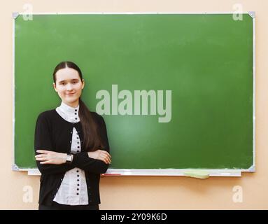 Glückliche Schüler Mädchen stehen in der Nähe von sauberen Tafel im Klassenzimmer Stockfoto