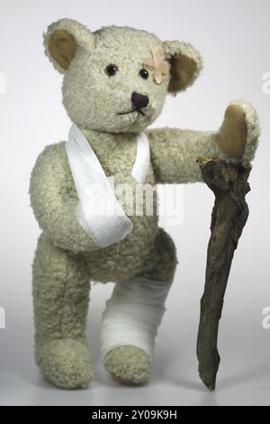 Verletzter Teddy mit Stock Stockfoto