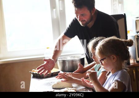 Vater und seine zwei kleinen Helfer. Kinder kochen hausgemachtes Brot mit es Vater Stockfoto