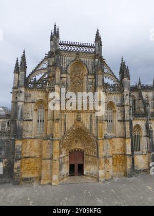 Beeindruckende gotische Kathedrale mit reich verzierten Lanzettenfenstern und reichen Details an der steinfarbenen Fassade unter bewölktem Himmel, Blick aus der Luft, Monast Stockfoto