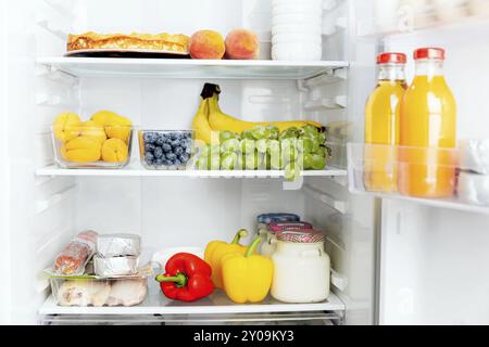 Vorderansicht des offenen zweitürigen Kühlschranks oder der Kühlschranktür gefüllt mit frischem Obst, Gemüse, Saft, voller gesunder Lebensmittel und Zutaten Stockfoto