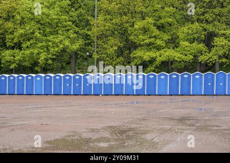 Eine Reihe tragbarer Toiletten vor einem Wald Stockfoto