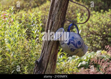 Keramikkkrug hängt an einem Holzpfosten in einem grünen Garten, Eibergen, Gelderland, Niederlande Stockfoto