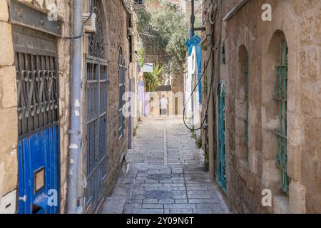 Eine typische Gasse in den alten Vierteln von Jerusalem, Israel, mit Steinhäusern und Pflaster und farbenfrohen Metall Sicherheitsriegeln an allen Fenstern und Stockfoto