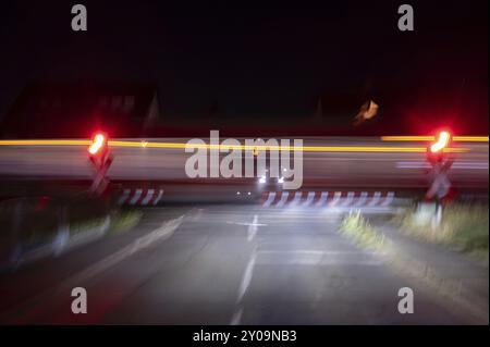 Vorbeifahrender Zug an einem Bahnübergang mit Barrieren bei Nacht, Eckental, Mittelfranken, Bayern, Deutschland, Europa Stockfoto