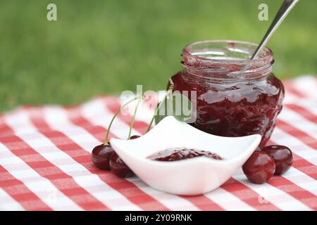 Glas Kirschmarmelade und einige Kirschen auf der Serviette Stockfoto