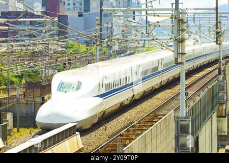 KYOTO, JAPAN, 21. JUNI 2015: Heck eines abfahrenden Hochgeschwindigkeitszuges von Shinkansen, der Kyoto zwischen Drähten und Gebäuden verlässt, die von oben gesehen werden Stockfoto