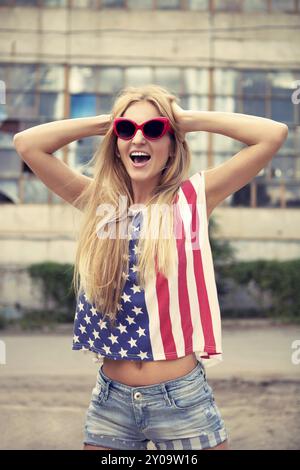 Blondes Mädchen hält die Hände auf den Kopf stehend auf beschädigte Tankstelle Stockfoto