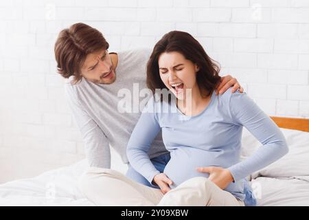 Sorgen Mann die schwangere Frau trösten, dass das Leiden von pränatal Kontraktionen Stockfoto