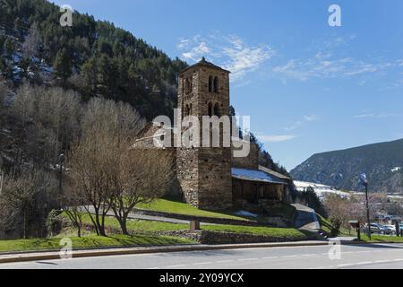 Mittelalterliche Steinkirche an einer Strasse, umgeben von Baeumen und Bergen unter einem blauen Himmel, Kirche Sant Joan de Caselles, Canillo, Pyrena Stockfoto