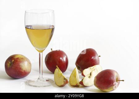 Apfelsaft im Glas, rote Äpfel, einer davon in Scheiben geschnitten, Hintergrund weiß Stockfoto