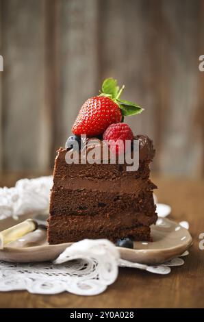 Stück Schokolade Kuchen mit Zuckerguss und frischen Beeren auf hölzernen Hintergrund Stockfoto