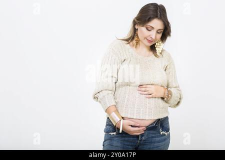 Junge hübsche schwangere Frau in Freizeitkleidung im Studio Stockfoto