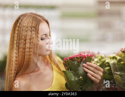 Junge Frau, die Blumen in einem Garten-Center zu kaufen. Getönten Farbbild Stockfoto