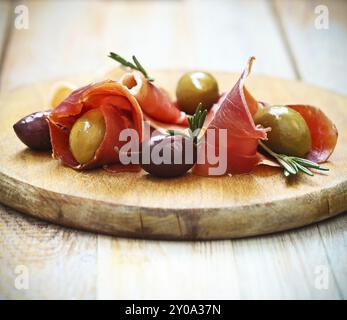 Schinken mit Oliven und Rosmarin auf dem hölzernen Hintergrund Stockfoto