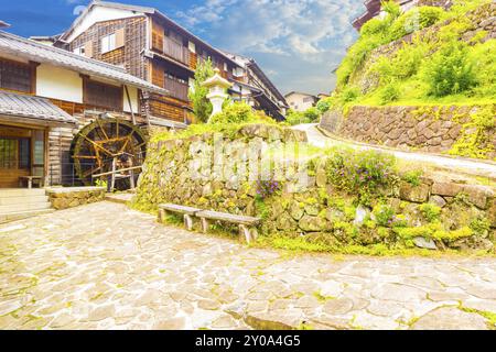 Traditionelle Holzhäuser und Wasserräder säumen den Steinweg auf diesem wunderschön restaurierten Abschnitt der historischen Nakasendo-Straße aus der Edo-Zeit im Bahnhof Stockfoto