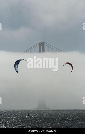 Ein Paar Kitesurfer genießen eine nebelige Fahrt in der Nähe der Golden Gate Bridge in San Francisco Stockfoto