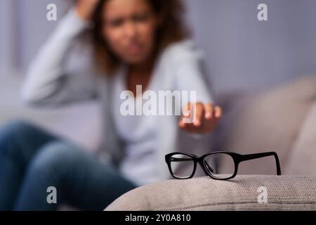 Afro-Frau mit Sehproblemen, Brillen auf dem Sofa zu suchen Stockfoto