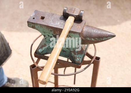 Farrier-Werkzeuge aus nächster Nähe auf der ländlichen Pferdefarm. Hintergrund des Reitsports. Ausrüstung und Hammer ruhen auf dem alten Amboss. Stockfoto