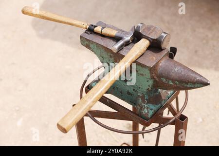 Farrier-Werkzeuge aus nächster Nähe auf der ländlichen Pferdefarm. Hintergrund des Reitsports. Ausrüstung und Hammer ruhen auf dem alten Amboss. Stockfoto