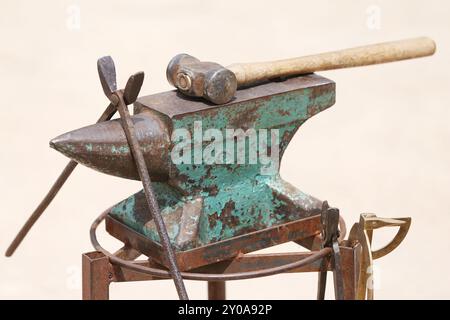 Farrier-Werkzeuge aus nächster Nähe auf der ländlichen Pferdefarm. Hintergrund des Reitsports. Ausrüstung und Hammer ruhen auf dem alten Amboss. Stockfoto